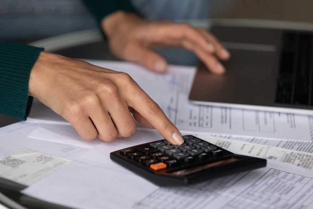 stock-photo-close-up-woman-using-calculator-and-laptop-calculating-domestic-bills-finances-checking-2021633258