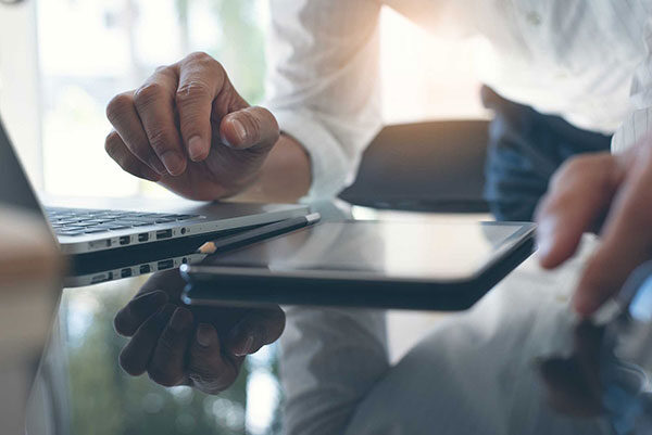 Hands with a tablet and laptop on the table